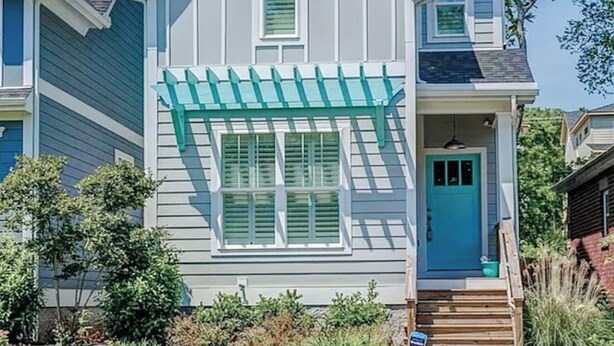 A two-story house with a blue front door, a covered porch, and a well-maintained lawn. - The Teal Door Cottage-Spacious home with King suite (Nashville)