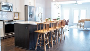 A modern kitchen with white cabinets, stainless steel appliances, and a central island with bar stools. - The Teal Door Cottage-Spacious home with King suite (Nashville)