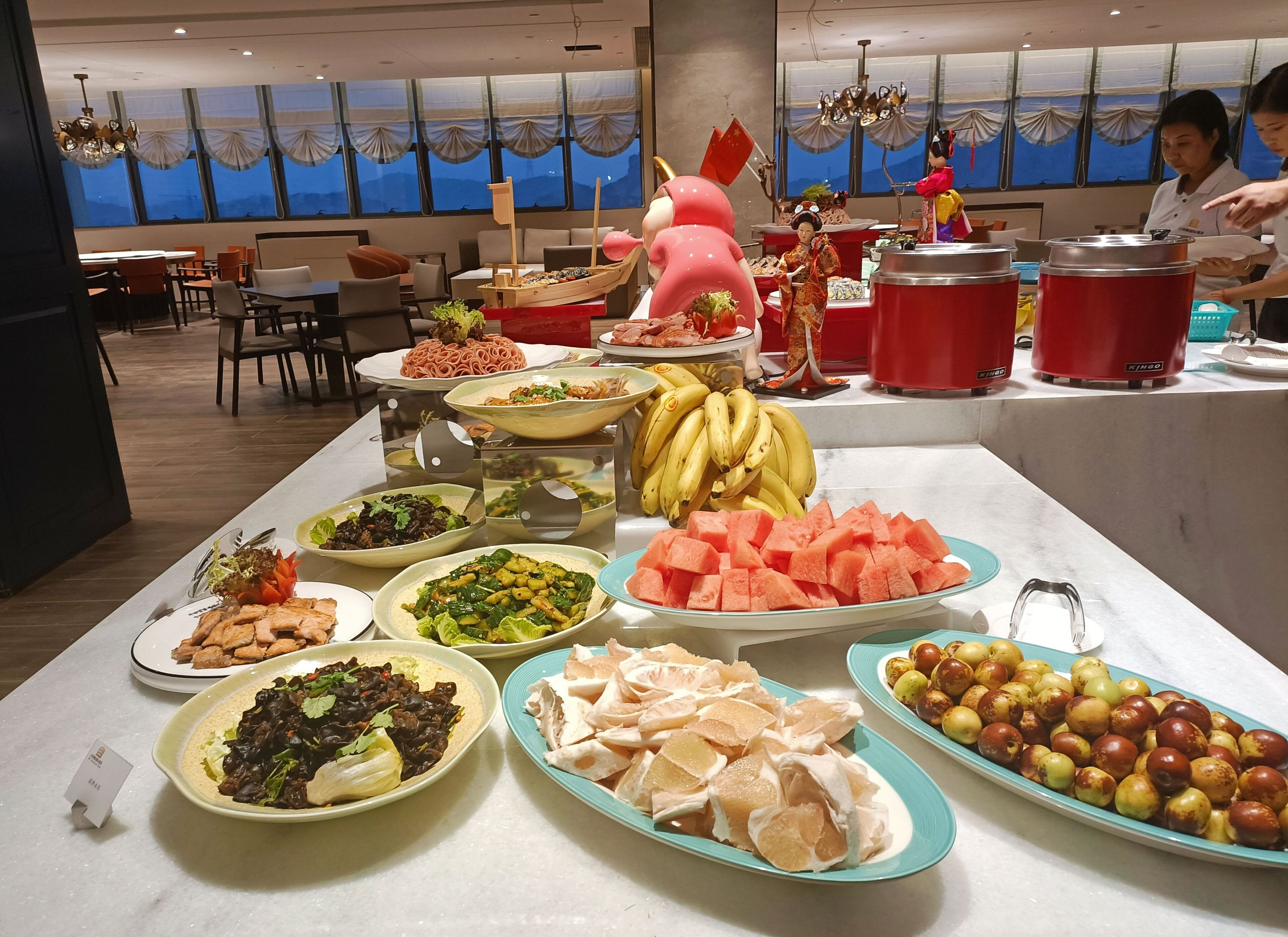 Un buffet proposant une variété de plats, notamment des fruits, des légumes et des viandes.