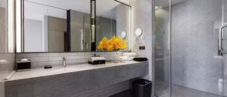A modern bathroom with a large mirror, a glass shower enclosure, and a marble countertop.