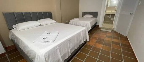 Een hotelkamer met twee bedden, een badkamer met douche en een betegelde vloer.