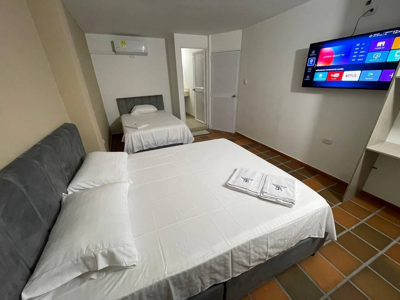 Een hotelkamer met twee bedden, een flatscreen televisie en een betegelde vloer.