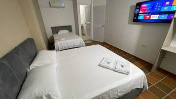 Een hotelkamer met twee bedden, een flatscreen televisie en een betegelde vloer.