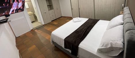 Habitación de hotel con cama, televisión, armario y baño.