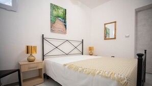 A bedroom with a bed, bedside tables, a painting, and a mirror. - Piccola Stella | studio apartment in Torre Lapillo (Porto Cesareo)