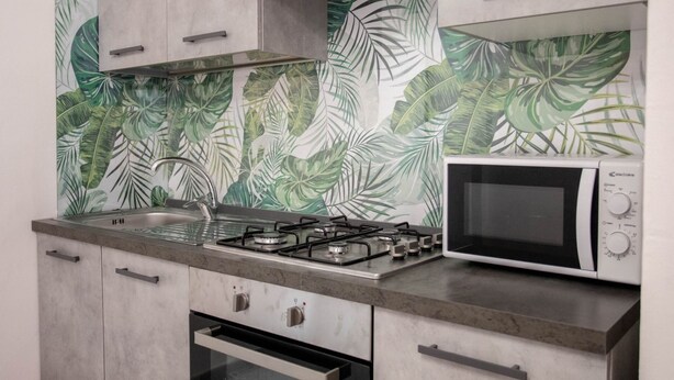 A kitchen with a gas stove, a microwave, and a sink. - Piccola Stella | studio apartment in Torre Lapillo (Porto Cesareo)