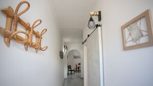 Un pasillo con un adorno de pared de madera, una lámpara y un cuadro enmarcado.