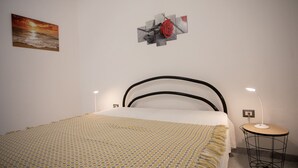 Un dormitorio con una cama, una mesita de noche con lámpara y decoración en la pared.