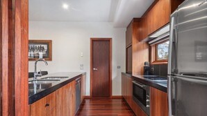 Een moderne keuken met houten kastjes, roestvrijstalen apparatuur en een zwart aanrecht.