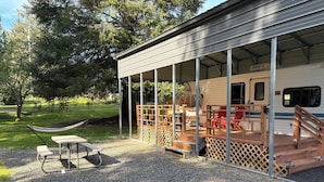 A covered outdoor area with a picnic table, a hammock, and red chairs. - 1-bedroom camper trailer minutes from Olympic Peninsula (Forks)