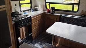 A compact kitchenette with a stove, sink, and a small countertop. - 1-bedroom camper trailer minutes from Olympic Peninsula (Forks)