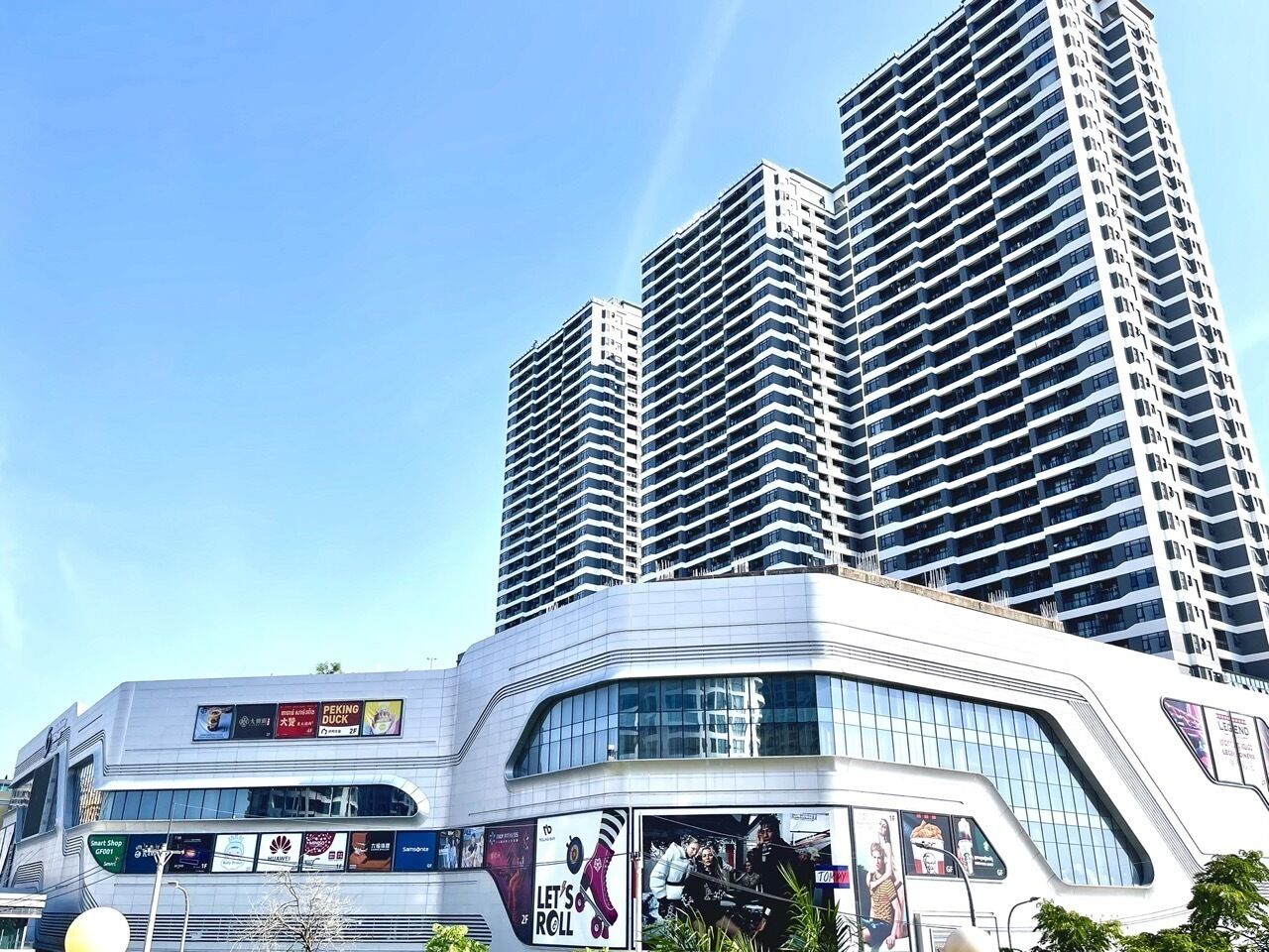 Een modern gebouw met een gebogen gevel, grote ramen en diverse advertenties.