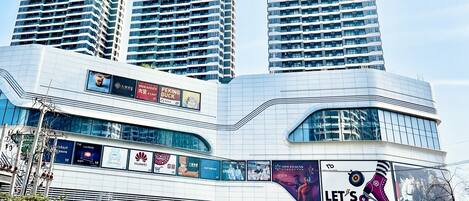A modern building with multiple floors, large windows, and various advertisements.