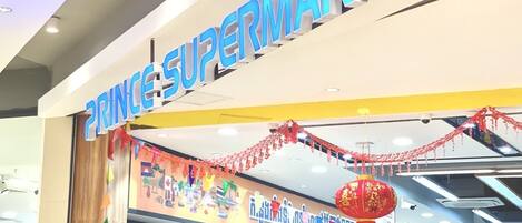 A supermarket entrance with a sign reading "PRINCES SUPERMARKET" and festive decorations.