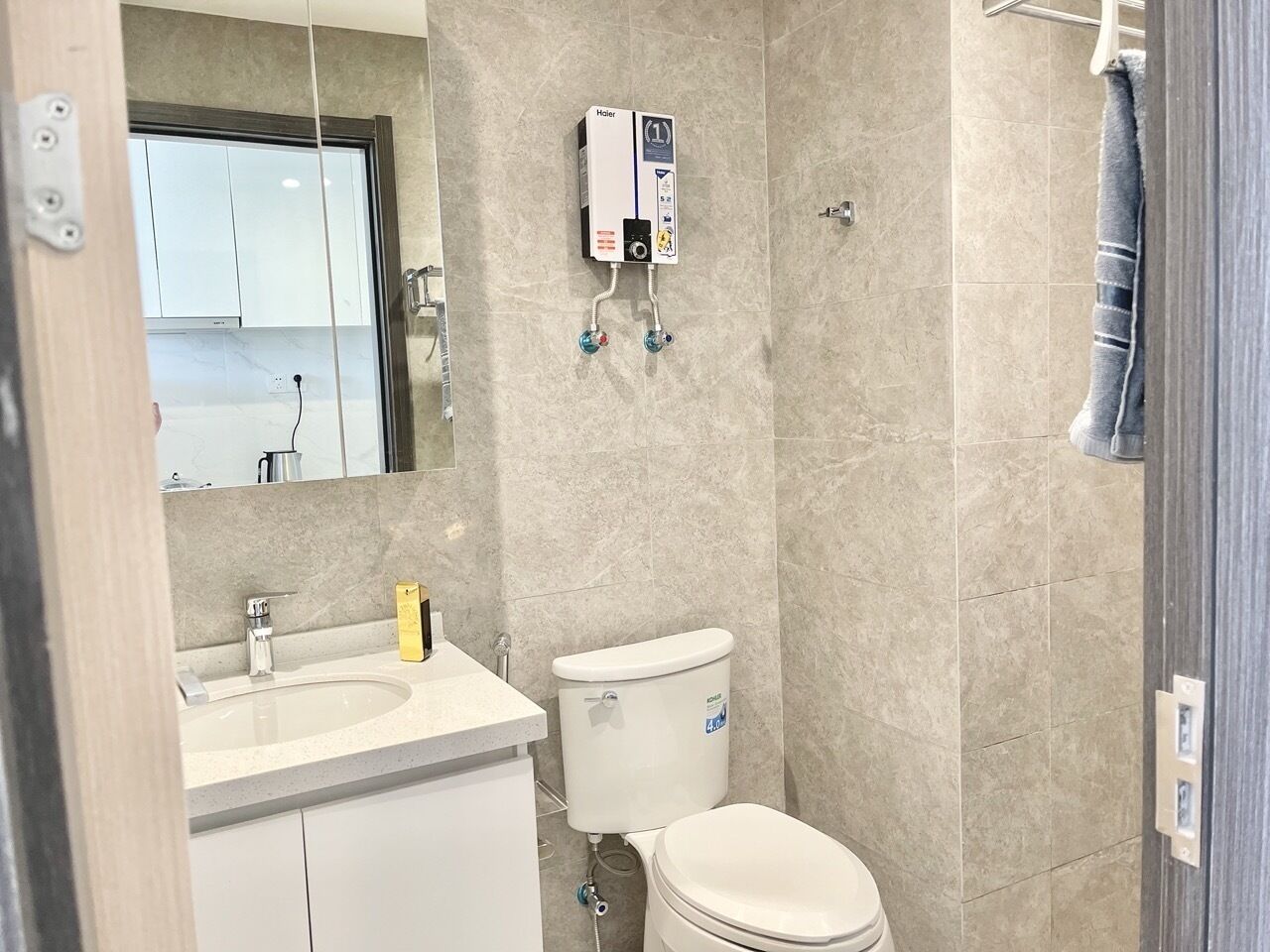 A bathroom with a toilet, sink, and a water heater mounted on the wall.