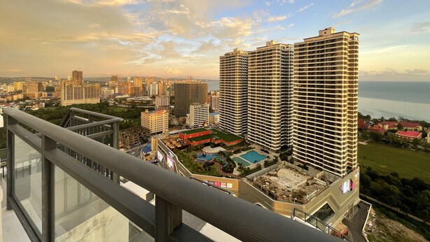 Um edifício alto com piscina no terraço e paisagem urbana ao fundo.