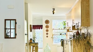 Una cocina amplia con armarios de madera, un comedor con mesa y sillas, y un tapete grande en el suelo.