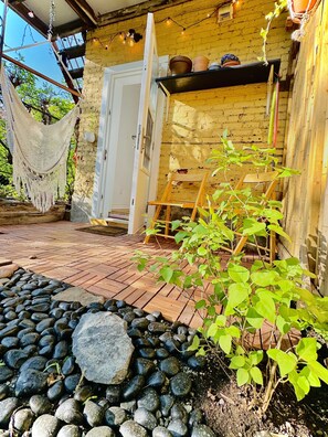 Eine Holzterrasse mit einer Hängematte, einem Holzstuhl und einem Blumentopf.