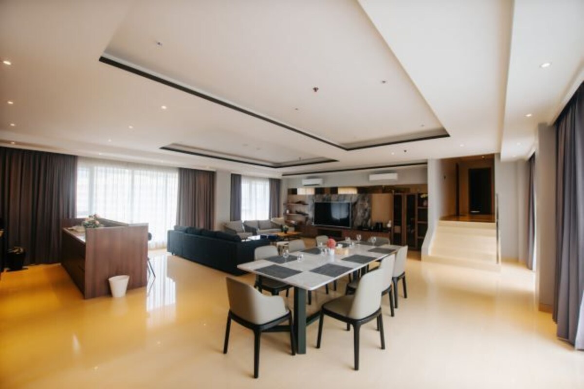 Une chambre d’hôtel moderne dotée d’un coin repas, d’un canapé, d’une télévision et d’un coin cuisine.