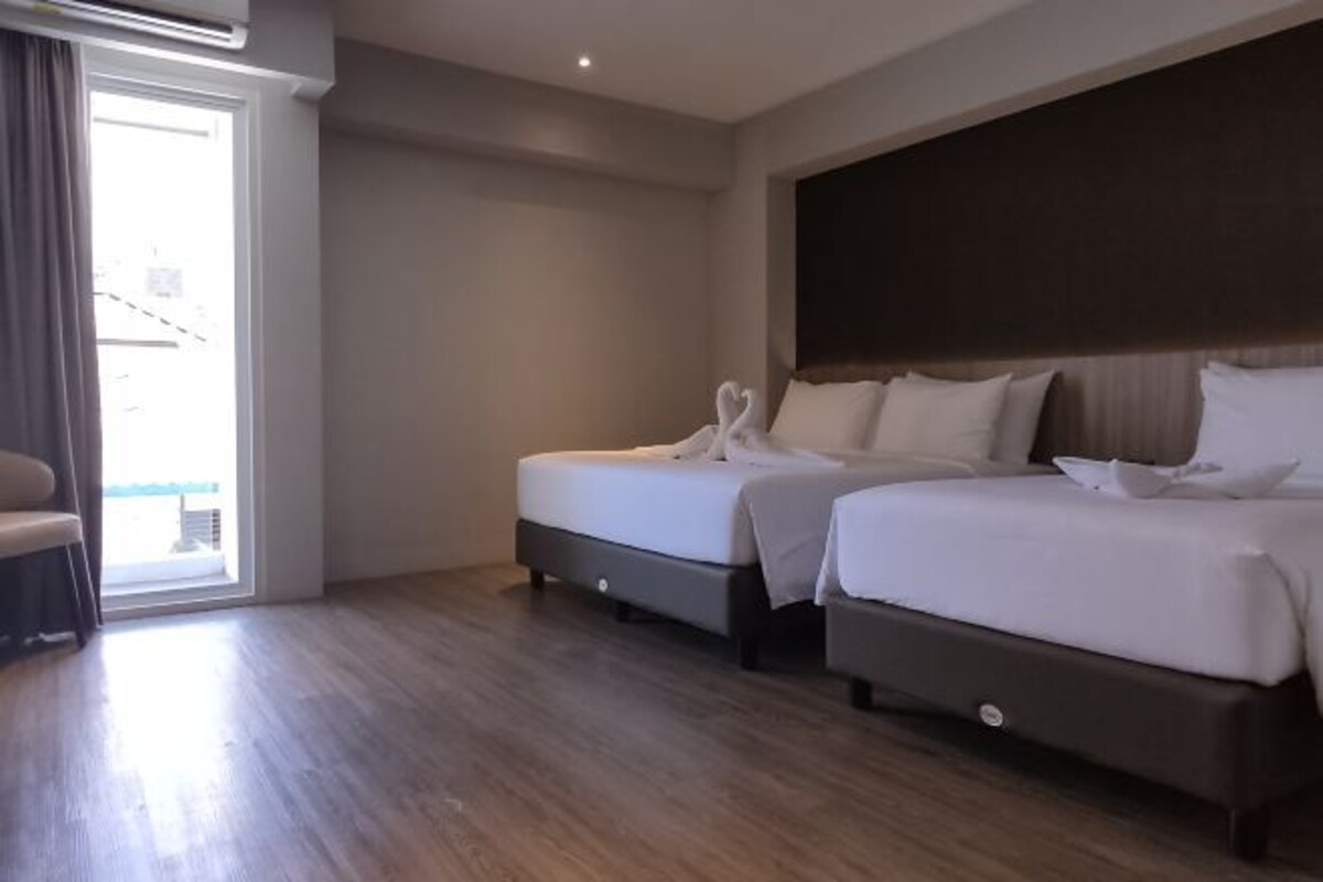 Une chambre d’hôtel avec deux lits, un canapé et une porte-fenêtre coulissante donnant sur un balcon.