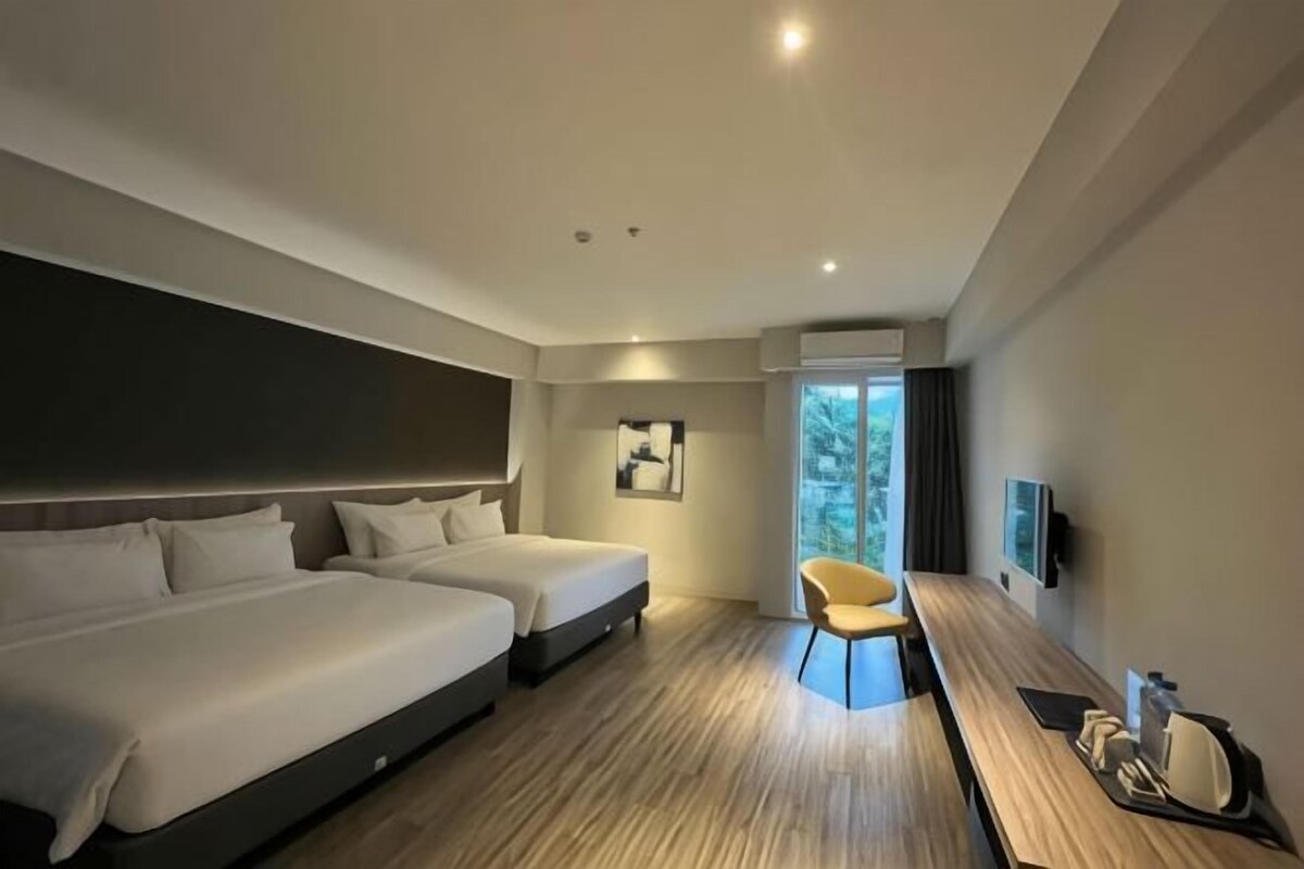 A modern hotel room with two beds, a desk, and a chair.