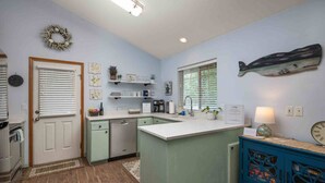 A kitchen with a central island, a built-in dishwasher, and a blue cabinet with decorative items. - Single Level Coastal Bungalow, Hot Tub, Pet Friendly, Fire Pit, Moments to Beach and Rockaway (Rockaway Beach)