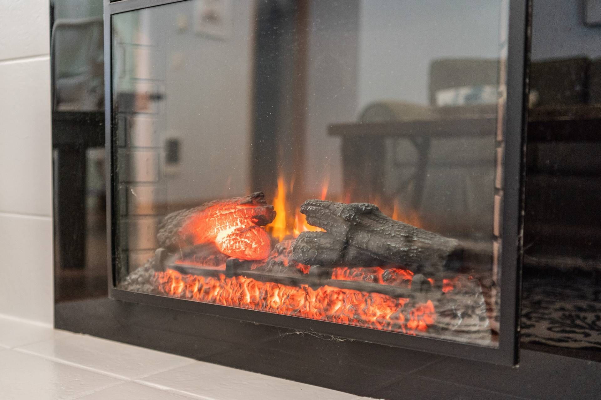 A glass fireplace with burning logs and embers.