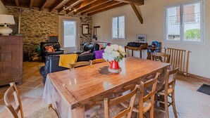 Amplia sala de estar con una mesa de comedor de madera, sofá de cuero y pared de piedra.