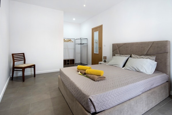 Une chambre à coucher avec un lit, une chaise, une armoire et un miroir.