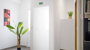 En gang med en potteplante, en dør og et lille skilt over den.