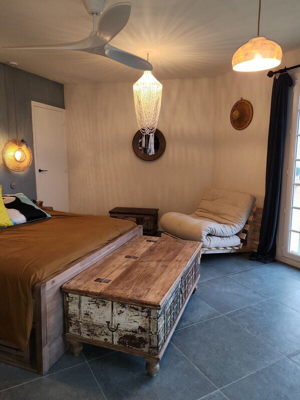 A bedroom with a bed, a wooden chest, a ceiling fan, and a hanging light fixture.