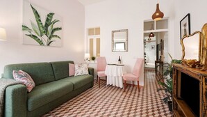Un soggiorno con un divano verde, un tavolo da pranzo con sedie, un pavimento decorato e un televisore su un mobile in legno.