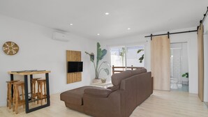 Una sala de estar moderna con un sofá marrón, una mesa de madera y un televisor montado en la pared.