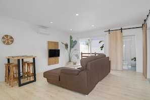 Una sala de estar moderna con un sofá marrón, una mesa de madera y un televisor montado en la pared.