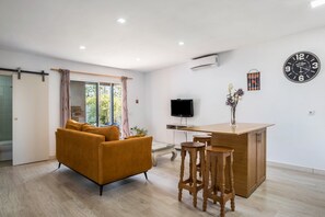 A modern living room with a sofa, a TV, a wooden bar, and a clock on the wall.