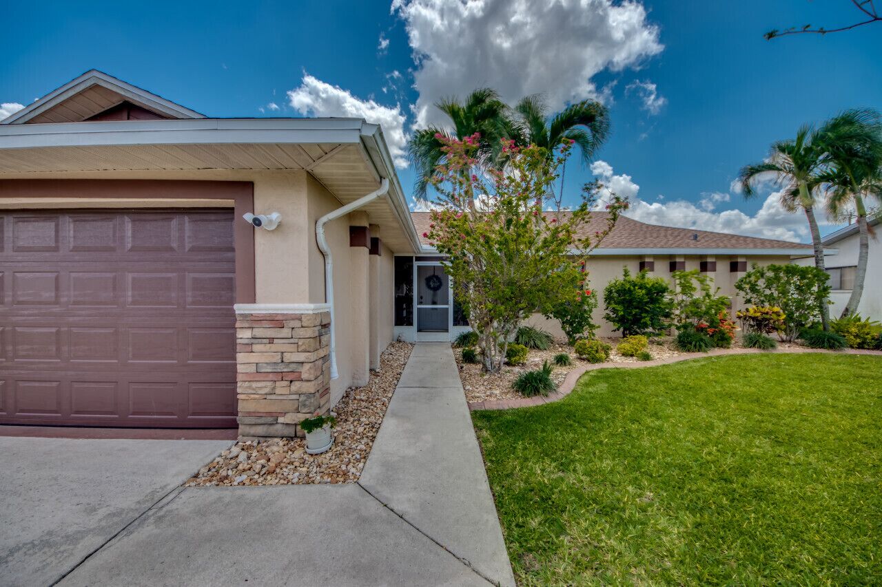 A residential house with a garage, a front porch, and a well-maintained lawn.