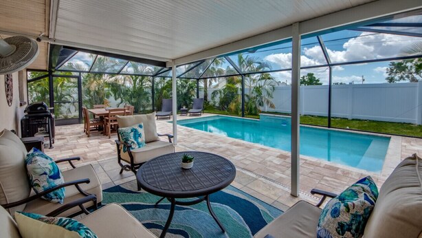 Un espacio al aire libre techado con piscina, mobiliario y vistas al exterior.