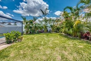 A well-maintained backyard with a lawn, various tropical plants, and a pool. - Sunshine POOL Cape Coral Home Centrally Located Great Outdoor Space (Cape Coral)