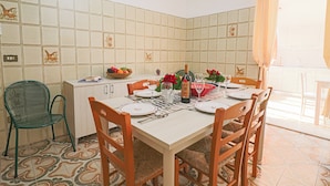 Un comedor con salpicadero de azulejos, una mesa preparada para cuatro personas y una silla verde.