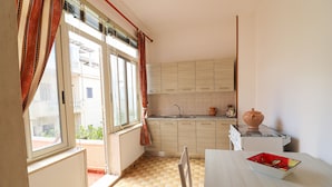 Una cocina con ventana, un lavamanos, armarios y una mesa con un cuenco.