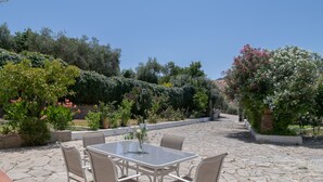 An outdoor patio with a table and chairs, surrounded by lush greenery and flowering plants. - Chalet 'Casa El Molino' with Mountain View, Wi-Fi and Air Conditioning (Montecorto)