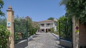 A gated entrance to a building with a stone pathway leading to a white building with a balcony. - Chalet 'Casa El Molino' with Mountain View, Wi-Fi and Air Conditioning (Montecorto)