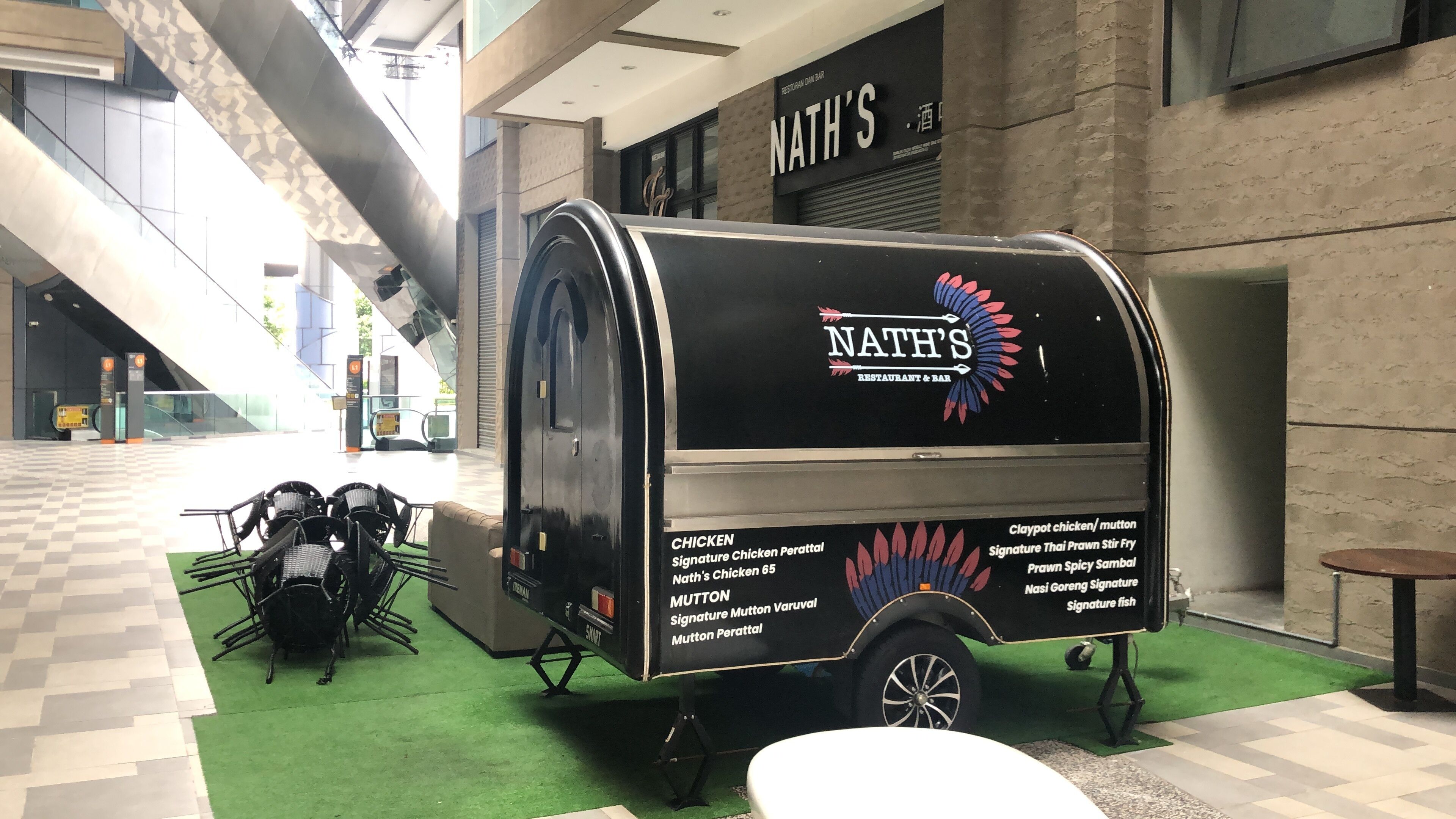 A food truck named 'NATH'S' parked in a modern indoor area with a checkered floor and a green carpet.
