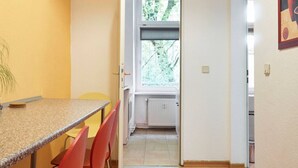 A narrow hallway with a window leading to a kitchen area.