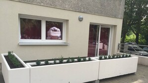 A building with a long white planter box with plants, a window, and a door. - Potsdamer Platz-Top Spot Studio 1 (Berlin)