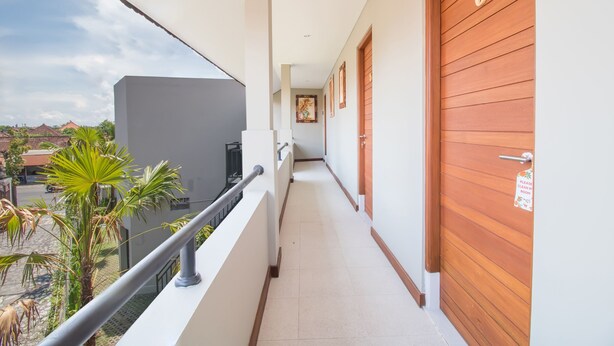 A corridor with a balcony, wooden doors, and a view of the outside.