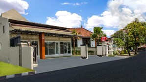 A modern building with a covered entrance, large windows, and a red sign.