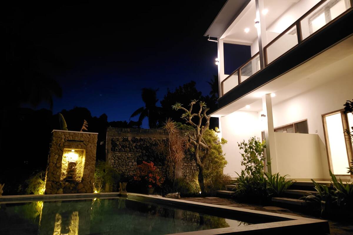 Uma casa moderna com piscina, paredes de pedra e varanda com vista para a piscina.