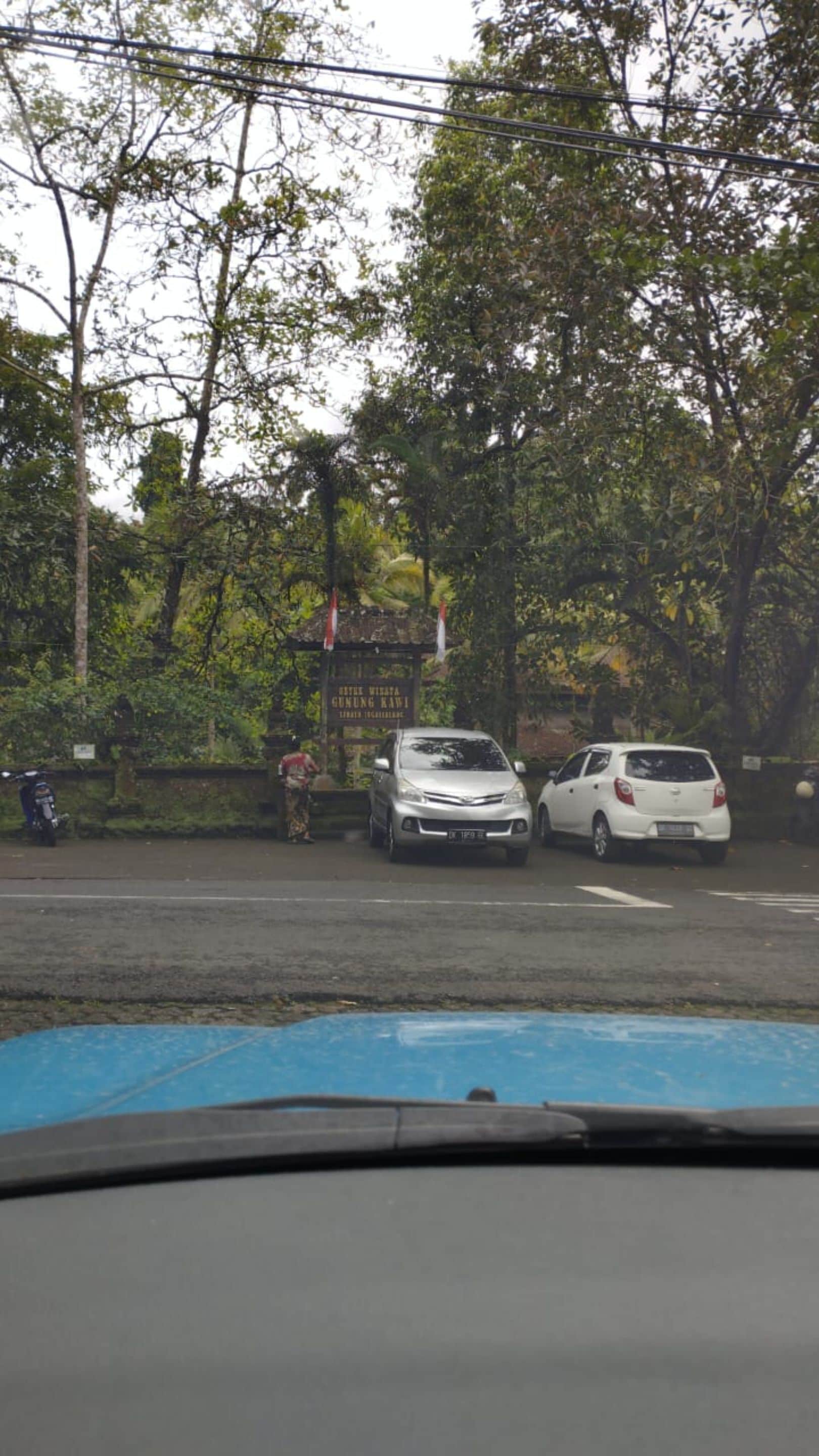 A parking area with two cars parked near a signboard.