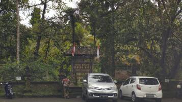 A parking area with two cars parked near a signboard.